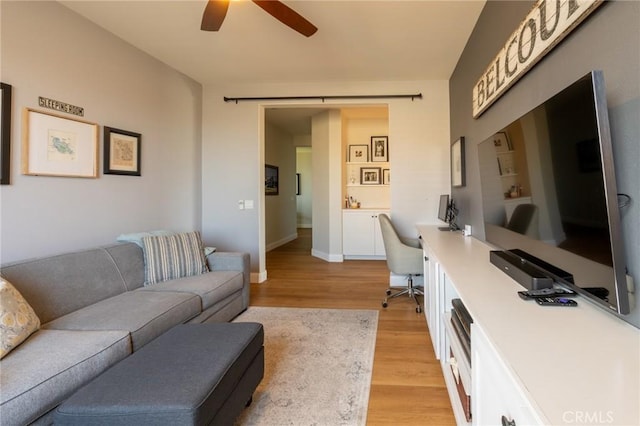 living room with baseboards, a ceiling fan, and light wood-type flooring