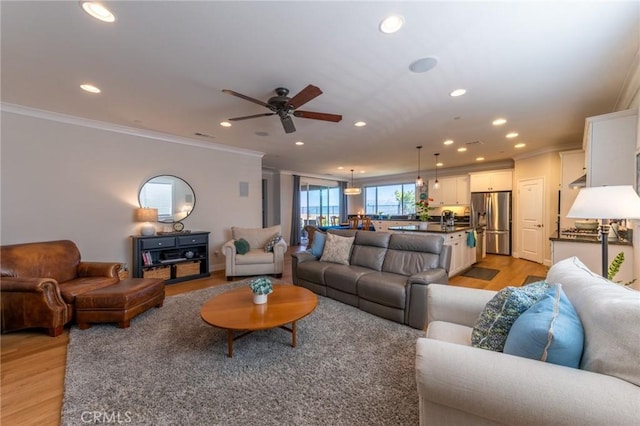 living room with a ceiling fan, ornamental molding, light wood-type flooring, and recessed lighting