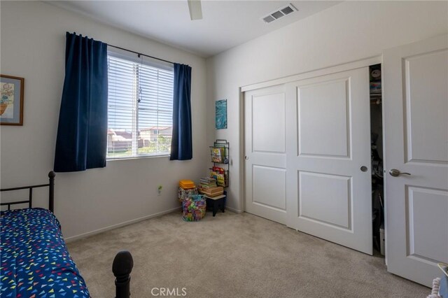 carpeted bedroom with baseboards, a ceiling fan, visible vents, and a closet