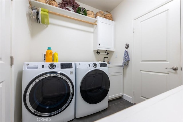 laundry room featuring cabinet space, dark tile patterned floors, washer and clothes dryer, and a sink