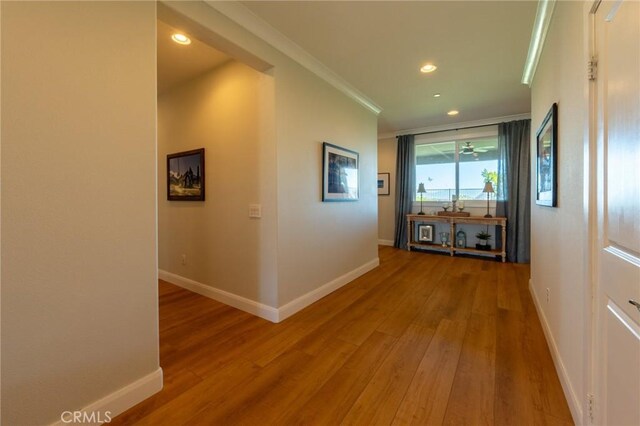 hallway with wood finished floors, baseboards, recessed lighting, and ornamental molding
