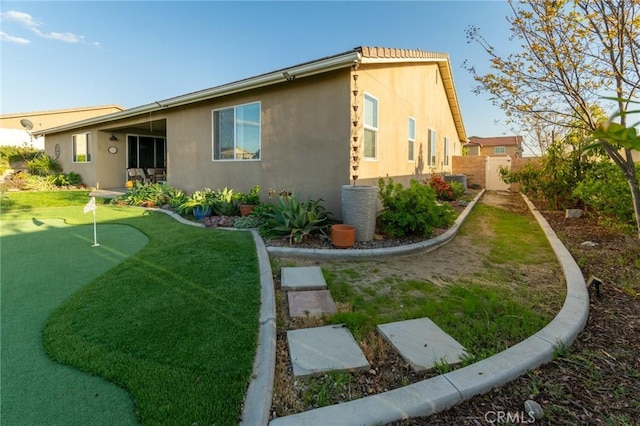 rear view of property featuring stucco siding and fence