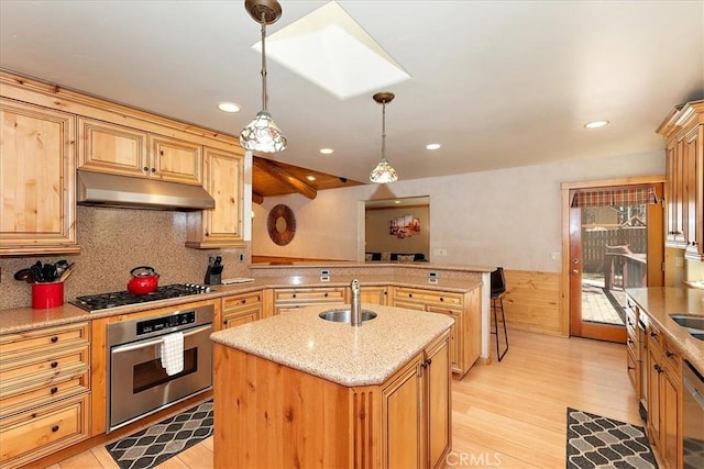 105 Olympic Dr, Big Bear Lake, CA 92315 - kitchen featuring a peninsula, under cabinet range hood, a kitchen island with sink, appliances with stainless steel finishes, and a sink