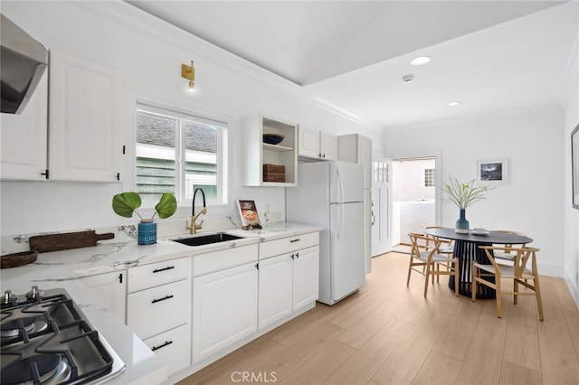 kitchen with freestanding refrigerator, stainless steel gas stovetop, ornamental molding, a healthy amount of sunlight, and a sink