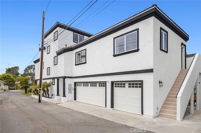 exterior space featuring an attached garage, stairway, and stucco siding