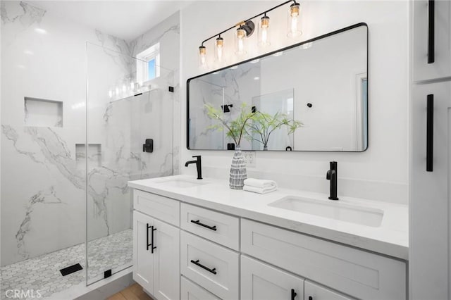 full bath featuring double vanity, a sink, and a marble finish shower