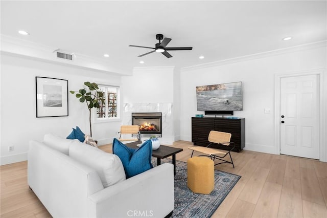 living room with a premium fireplace, light wood-type flooring, ceiling fan, and visible vents