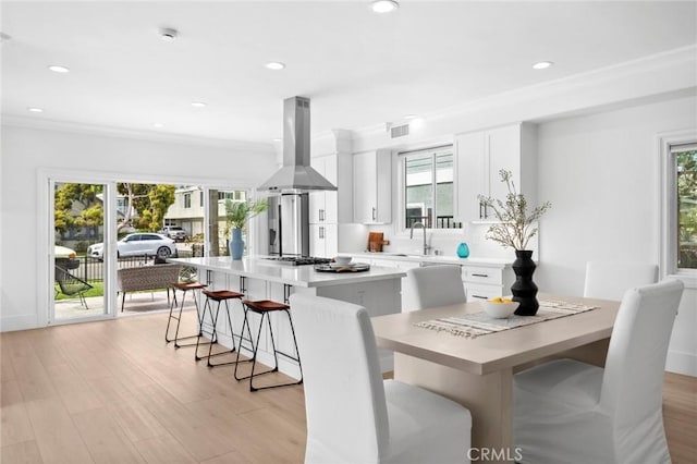 kitchen featuring a kitchen breakfast bar, a center island, island exhaust hood, and a healthy amount of sunlight
