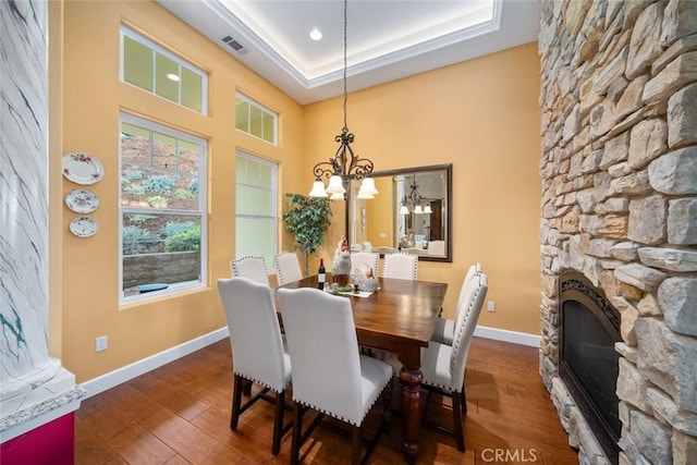 dining room featuring a fireplace, visible vents, baseboards, and wood finished floors