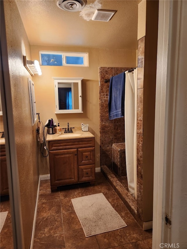 full bath with a shower stall, a textured ceiling, vanity, and visible vents