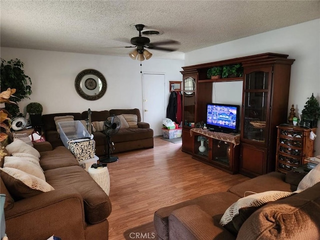 living room featuring light wood-style flooring, a textured ceiling, and ceiling fan
