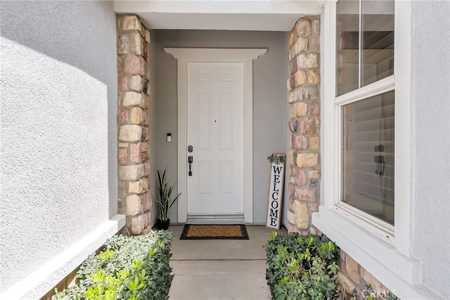 view of exterior entry with stucco siding and stone siding