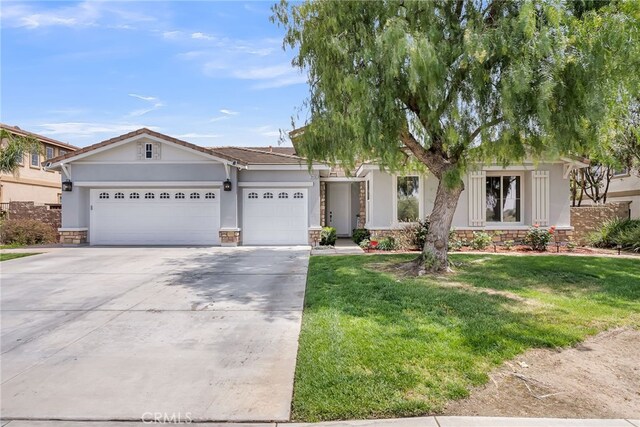 ranch-style home with stucco siding, a front yard, stone siding, an attached garage, and concrete driveway