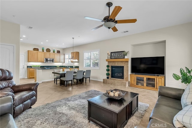 living room featuring visible vents, light tile patterned floors, a tiled fireplace, a ceiling fan, and recessed lighting