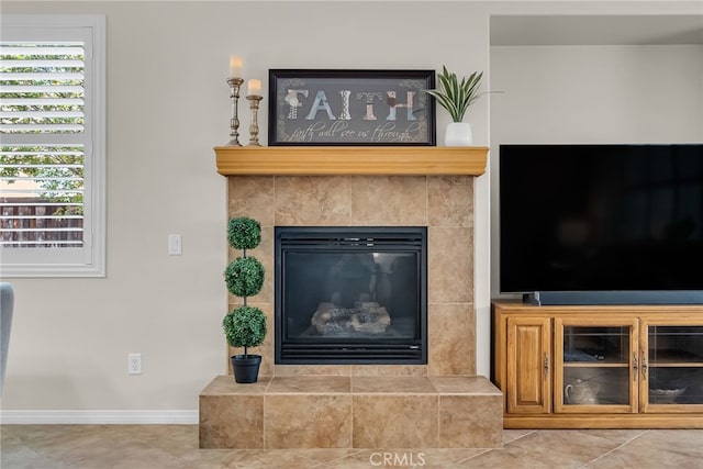 interior details featuring a tiled fireplace and baseboards