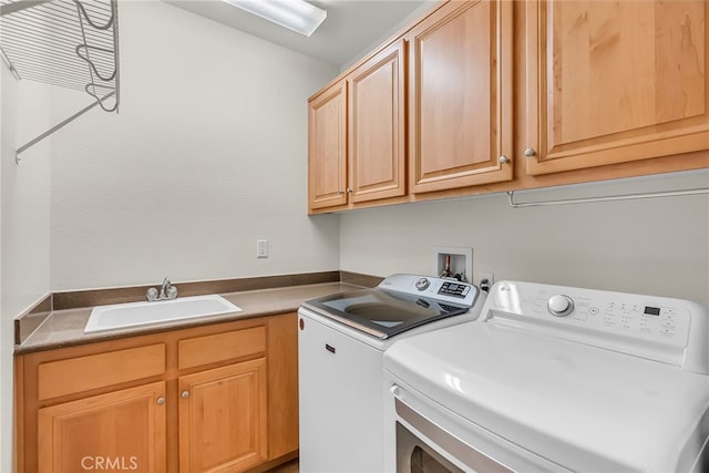 clothes washing area with a sink, cabinet space, and washer and clothes dryer