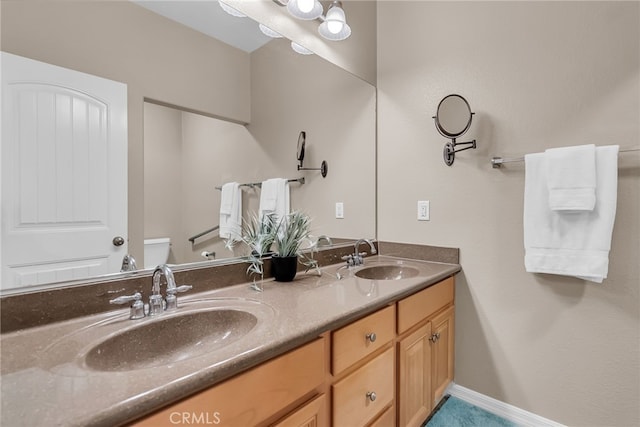 bathroom featuring toilet, double vanity, and a sink