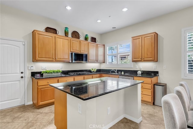 kitchen with recessed lighting, light tile patterned floors, a kitchen island, dark stone counters, and stainless steel appliances
