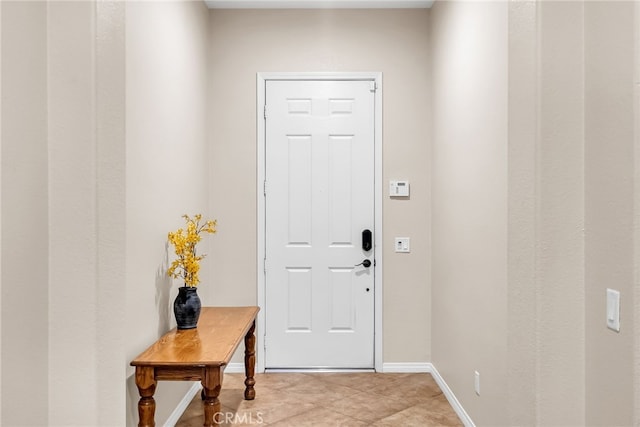 doorway with light tile patterned floors and baseboards