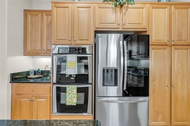 kitchen with dark stone counters, appliances with stainless steel finishes, and light brown cabinetry