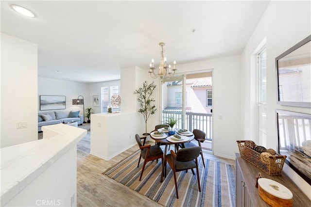 dining space featuring light wood finished floors, baseboards, and an inviting chandelier
