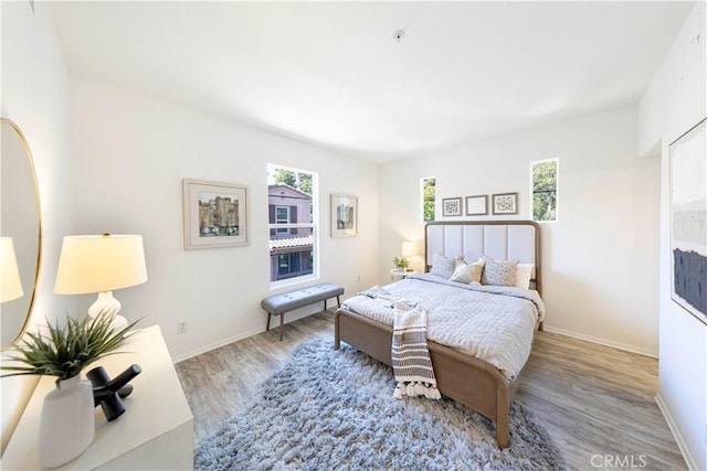 bedroom featuring baseboards, multiple windows, and wood finished floors