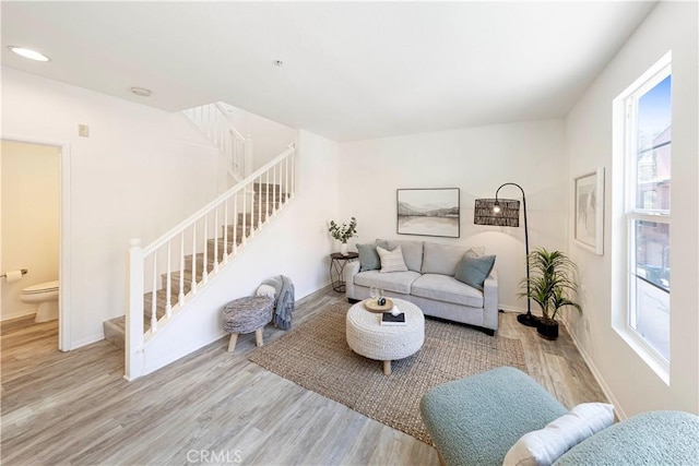 living area featuring a wealth of natural light, stairway, baseboards, and wood finished floors