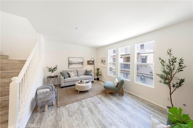 living area featuring baseboards, stairway, and wood finished floors