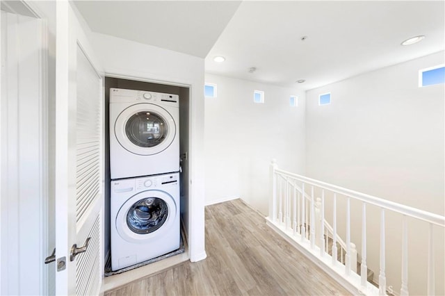 clothes washing area featuring recessed lighting, visible vents, stacked washer / drying machine, laundry area, and wood finished floors