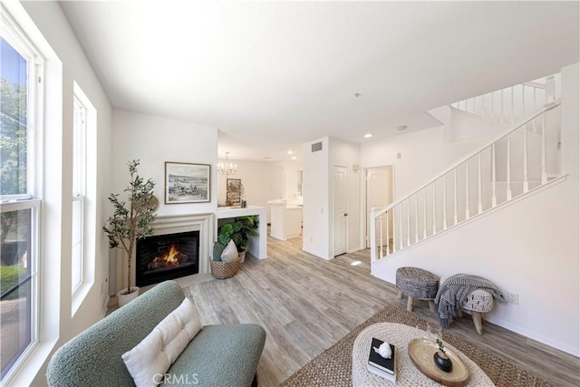 living room featuring light wood-type flooring, stairway, and a healthy amount of sunlight