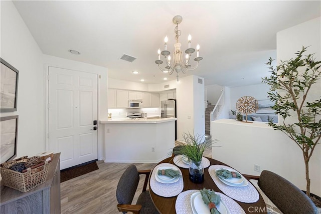 dining area with light wood-type flooring, visible vents, recessed lighting, a chandelier, and stairs