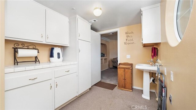 4176 Goss Rd, Phelan, CA 92371 - kitchen with light carpet, tile counters, and white cabinets