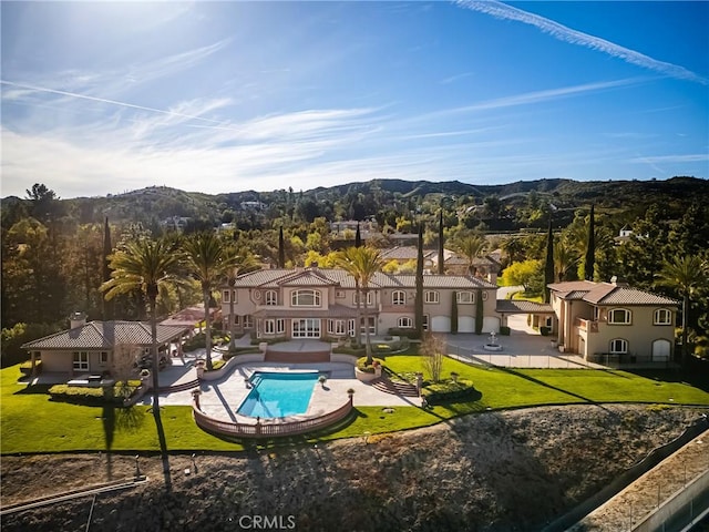 outdoor pool featuring a patio, a mountain view, and a lawn