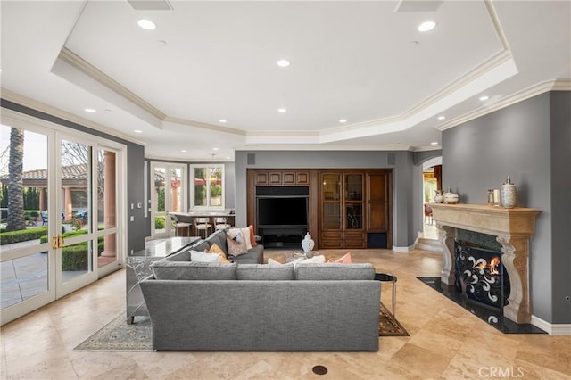 living room featuring ornamental molding, arched walkways, and a raised ceiling