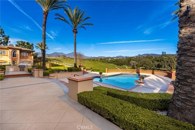 outdoor pool featuring a patio and a mountain view