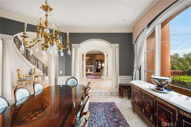 dining room with crown molding, a wainscoted wall, a decorative wall, ornate columns, and arched walkways