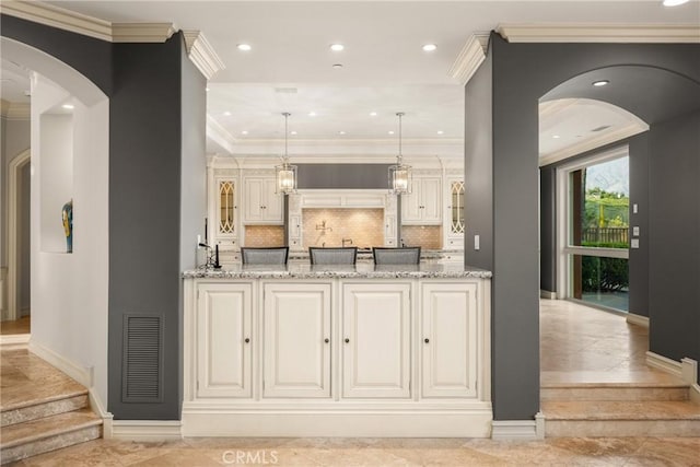 bar featuring decorative backsplash, visible vents, arched walkways, baseboards, and hanging light fixtures