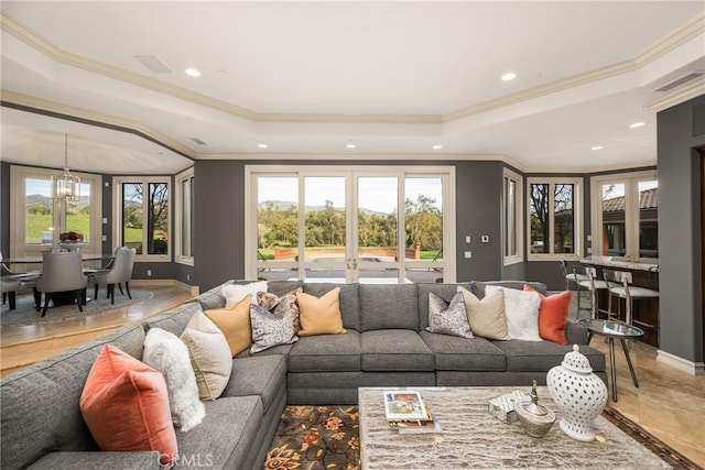 living room featuring an inviting chandelier, ornamental molding, and a tray ceiling