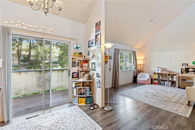 interior space featuring high vaulted ceiling, an inviting chandelier, wood finished floors, and visible vents