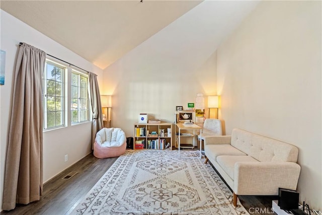 living area with high vaulted ceiling, wood finished floors, and visible vents