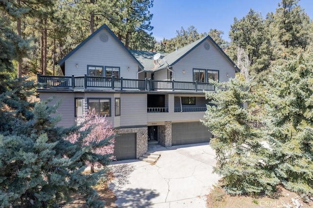 view of front facade with an attached garage, driveway, a balcony, and stone siding