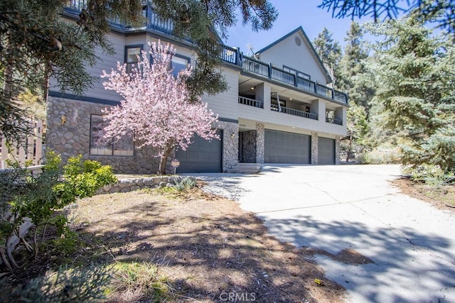 2405 Cedarwood Dr, Pine Mountain Club, CA 93222 - view of front of house with stone siding, a balcony, an attached garage, and concrete driveway