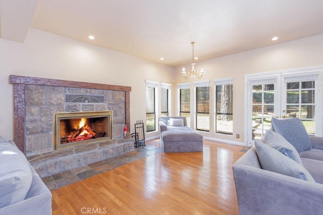living room featuring recessed lighting, a chandelier, a stone fireplace, and wood finished floors