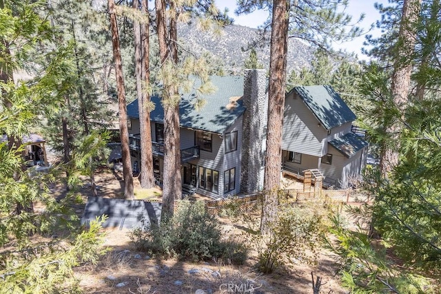 view of home's exterior featuring a mountain view, a balcony, and a chimney