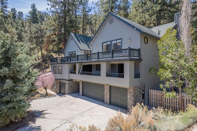 2405 Cedarwood Dr, Pine Mountain Club, CA 93222 - view of front of home with a balcony, a garage, stone siding, and concrete driveway