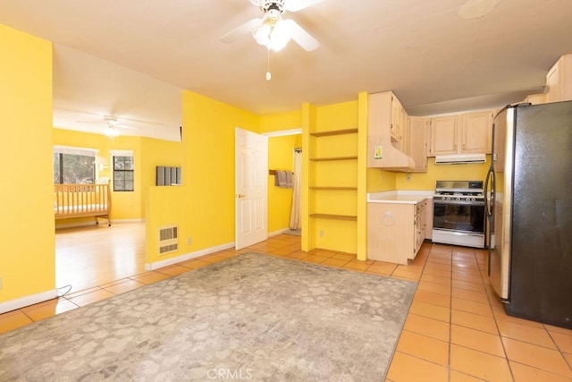 kitchen featuring freestanding refrigerator, a ceiling fan, light tile patterned floors, and gas stove