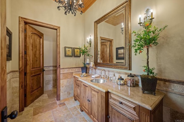 6314 El Apajo, Rancho Santa Fe, CA 92067 - bathroom featuring tile walls, vanity, stone tile floors, wainscoting, and a chandelier