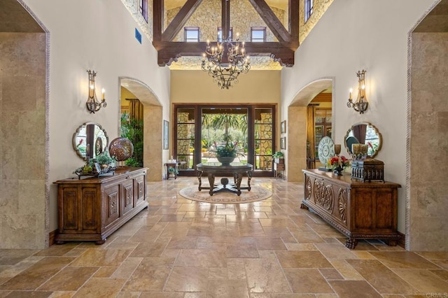6314 El Apajo, Rancho Santa Fe, CA 92067 - foyer featuring a towering ceiling, stone tile flooring, healthy amount of natural light, arched walkways, and a chandelier