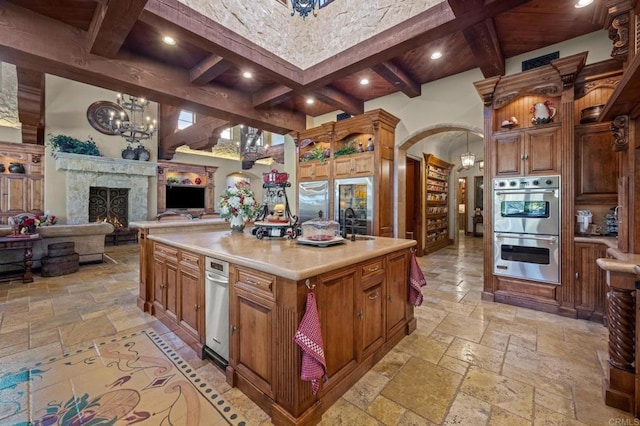 6314 El Apajo, Rancho Santa Fe, CA 92067 - kitchen featuring stainless steel double oven, stone tile flooring, light countertops, beamed ceiling, and a chandelier