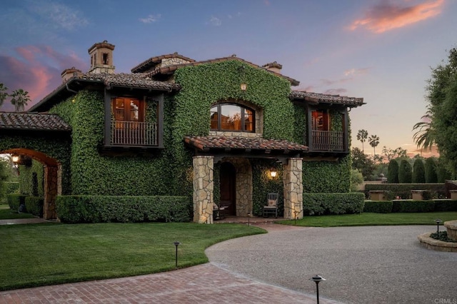 6314 El Apajo, Rancho Santa Fe, CA 92067 - view of front of home with a tiled roof, a balcony, a front lawn, and stone siding